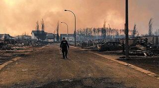 <p>Ein Polizist geht eine vom Feuer verwüstete Straße in Fort McMurray entlang.</p>