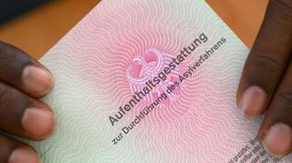 Er hat es geschafft: Ein somalischer Flüchtling hält eine Aufenthaltsgestattung in den Händen.