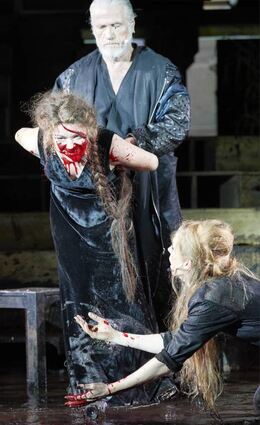 Etzel (Jürgen Prochnow) hält Swanhild (Linn Reusse, l.), die Schamanin (Pheline Roggan, r.) fängt ihr Blut auf.