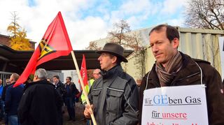 Zwei Mitarbeiter von General Electric protestieren vor dem Tor gegen den Arbeitsplatzabbau.
