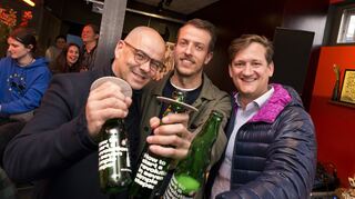 Max Spielmann von Welde und Frank Zumbruch vom UNCOVER Designfest überreichen Julian Bender im KIOSK die erste bedruckte Flasche.