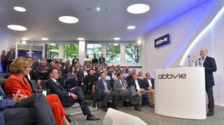 Festakt im Auditorium: Tom Hudson, Senior Vice President von AbbVie, steht am Rednerpult, links die rheinland-pfälzische Ministerpräsidentin Malu Dreyer.
