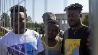 Migranten aus Kamerun stehen am Zaun eines Flüchtlingslagers in Vydeniai (Litauen). Belarus lässt die Asylsuchenden ungehindert ausreisen.