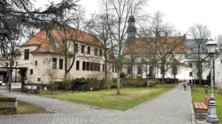 Der Pfarrer-Heinstadt-Weg liegt zentral, ist autofrei und führt am katholischen Kindergarten St. Nazarius (l.) vorbei. Er verbindet die Pfarrkirche (im Hintergrund) mit dem Stadthaus. Ein Hinweis auf den Ehrenbürger ist am Straßenschild angebracht.