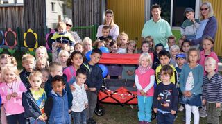 Die Kita-Kinder freuen sich ebenso wie Leiterin Moni Wilhelm (r.) über den neuen Bollerwagen.