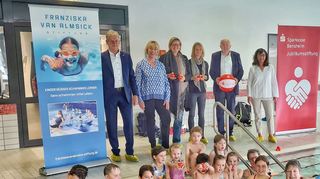 Offizielle Spendenübergabe bei der ersten Schwimmstunde für Erstklässler in Zusammenarbeit mit der Franziska-van-Almisick-Stiftung: (v.l.) Bürgermeister Helmut Glanzner, Stiftungsmanagerin Melanie Magin, Schulleiterin Sandra Aust, Konrektorin Christina Schmidt, Dieter Becher (Vorstandsmitglied der Jubiläumsstiftung der Sparkasse Bensheim), Birgit Kissel (Sparkasse Bensheim) sowie – im Becken – die Kinder mit den Schwimmlehrerinnen der SSG Bensheim.