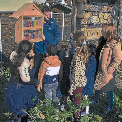 (hinten) befestigt das Insektenhotel, das   der Nachmittagsbetreuung der Schloss-Schule gemeinsam mit Vera  (rechts) gebastelt haben.