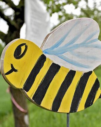 Kinder können Bienen und Blumen aus Holz bemalen.