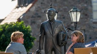 Die Bronzestatue von Max Teichmann (links Bild) scheint dem Gespräch interessiert zu folgen – wer war dieser Mann, dessen Ebenbild am Anfang der Scheuergasse steht? Der Firmensitz der Brain AG in der Darmstädter Straße (rechts) ist ein architektonisches Schmuckstück, was wurde hier früher hergestellt?