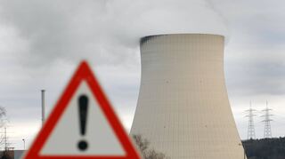 Ein Warnschild steht vor dem Kühlturm des Atomkraftwerkes Isar 1 und 2 nahe Essenbach (Niederbayern).