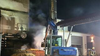 Nach ersten Löscharbeiten wurden die qualmenden Hackschnitzel mit Hilfe eines Baggers auf den Betonboden geschaufelt und abgelöscht.
