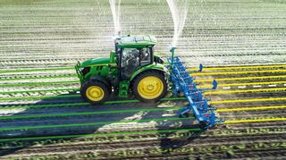 Ein Traktor hackt das Feld. Die bunten Linien hat das Spurführungssystem von John Deere automatisch erstellt.