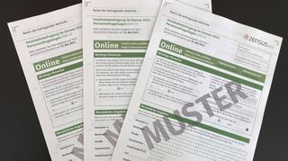 Drei Muster-Personenfragebögen zur Haushaltsbefragung im Zensus 2022 liegen auf einem Tisch.