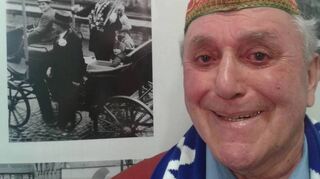 Urgestein der Heppenheimer Fastnacht: Hans Eberhard, im Hintergrund ein Foto aus seiner Zeit als Zugmarschall.