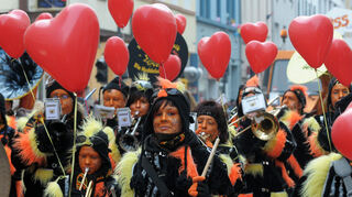 Umzugsteilnehmer laufen am Sonntag (14.02.2010) beim Fasnachtszug in ihren Kostümen und mit roten Luftballons in Herzform durch eine Straße in Ludwigshafen am Rhein.