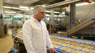 GeschäftsführerOliver Heinisch prüft beim Rundgang in der Produktioneine Verpackung.