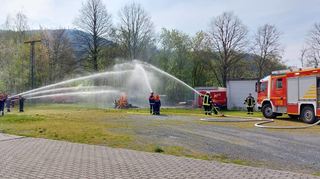 Mit vereinten Kräften bekämpften die Jugendfeuerwehren aus den Nachbarkommunen die Flammen eines brennenden Holzstapels.
