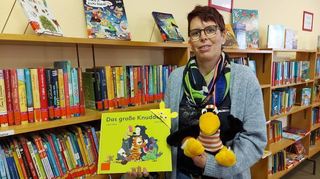 Uschi Herberg mit Lesekisten-Rabe Fridolin und dem Kinderbuch „Das große Knuddeln”.