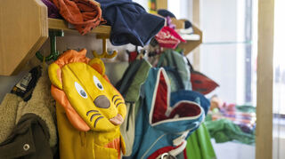 Kinderrucksäcke hängen in einer Garderobe einer Kita.