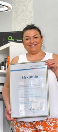 Fatma Oker mit der Urkunde in ihrem Geschäft.