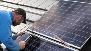 Der Mitarbeiter einer Solarfirma montiert Photovoltaikmodule auf dem Dach eines Wohnhauses. Zuvor sollte die Anlage schon versichert sein.