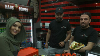 Birsel Demirbas, Ugur Mamak und einer der weiteren sieben Mitarbeiter präsentieren den Döner.