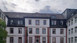 Das aktuelle Foto lässt den alten Hospitalbau mit seinem durch die Ecklisenen betonten Mittelrisalit zwischen den viel jüngeren großen Anbauten noch gut erkennen. Die hier sichtbare Pforte war 1955 von der Hauptstraße in die Mathildenstraße verlegt worden.