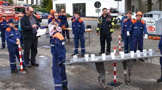 Unter den strengen Augen von Einhausens Gemeindebrandinspektor Christoph Röll (links) transportierten Mitglieder der Jugendfeuerwehr Hüttenfeld mit verbundenen Augen zehn volle Wasserbecher auf einer Trage durch einen Parcours. Ihre Kameraden halfen ihnen mit Zurufen wie „Vorsicht, vorne anheben, jetzt geradeaus“.