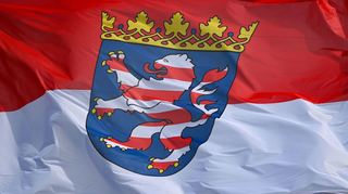 Die hessische Landesdienstflagge, die rot-weiße Landesflagge mit dem Landeswappen in der Mitte, weht im Wind.
