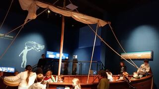 Erstkommunionkurs fährt ins Bibelmuseum
54 Teilnehmer  42 Kommunionkinder der Kath. Pfarreien Krumbach,Fürth, Lindenfels und Rimbach und 12 erwachsene Begleitpersonen machten sich am Samstag, 18. Nov. 23 auf den Weg nach Frankfurt. Die Leitung hatten Pfr. Wolfgang Kaiser und die Kommuniongruppenleiter/-innen. Ziel war das Frankfurter Bibelhaus. Dort wurden sie in einer Führung in die Zeit Jesu und auch in die Zeit des Alten Testamentes hineinversetzt. Bilder, Schautafeln und Gegenstände wie das Schofar-Horn, Fischernetze, Krüge und Münzen ließen die biblischen Geschichten lebendig werden. Die Teilnehmer konnten in ein nachgebautes Fischerboot einsteigen und nachfühlen: Wie ist es den Jüngern auf dem See Gennesareth ergangen? Wie haben die Menschen gelebt? Wie hat es im Tempel, dem Haus Gottes ausgesehen, in dem auch Jesus aufgetreten ist? Die Kommunionkinder konnten auch eine Handmühle betätigen, so wie früher und die mühselige Arbeit der Leute damals nachfühlen. Nach einem mit Eindrücken erfüllten Tag ging es dann am Nachmittag wieder zurück in den Odenwald.