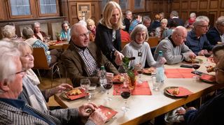 Im Nibelungensaal trafen sich Mitglieder des Lorscher Partnerschaftsvereins um Sprecherin Brunhilde Schieb (stehend) bei Wein und Königskuchen. Elmar Ullrich unterhielt die Teilnehmer mit Akkordeon-Musik und einer Geschichte aus seinem Buch, in dem es um ein Bild des Malers Yvan Nys ging.