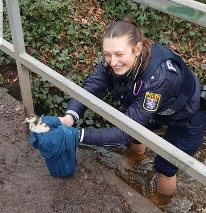 Eine Polizistin stieg barfuß in den Bach und befreite die Jungvögel.