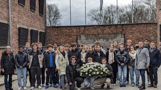 Oberstufenschülerinnen und -schüler der Geschwister-Scholl-Schule besuchten im Rahmen einer Projektreise das Konzentrationslager Auschwitz. An der „Schwarzen Wand“ legten sie ein Gesteck nieder.