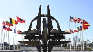 Die Nationalflaggen der Mitgliedsländer wehen im NATO-Hauptquartier Brüssel an der Stahlskulptur des b Architekten Raymond Huyberechts, die einen Kompass – das NATO-Logo – darstellen soll.