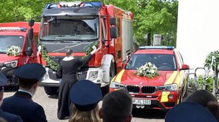 Vor dem Paul-Schnitzer-Saal parkten die neuen Feuerwehrautos. Pfarrer Michael Bartmann nahm die Fahrzeugsegnung vor.