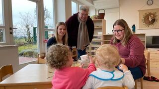 Pfarrer Sebastian Hesselmann, die Erzieherinnen Anna Höbel und Verena Bodenmüller mit zwei Kindern beim Mittagessen in der neuen Kita-Außenstelle „Morgenstern-chen“.