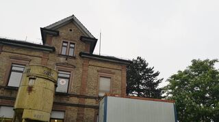 Die Bücherei ist derzeit auf zwei Seiten von der Tiefbaustelle umgeben und zur Straßenseite von Containern und Baustellengerät verdeckt.