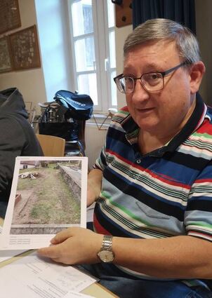 Ortsbeiratsmitglied Rolf Ihrig zeigt ein Foto mit Spuren, die ein Baufahrzeug auf dem Friedhof in Winterkasten hinterlassen hat.