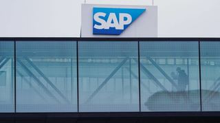 Ein Mann geht über eine verglaste Brücke zwischen zwei Firmengebäuden von SAP in Walldorf.