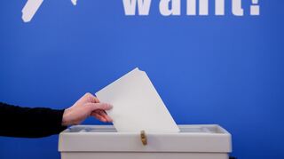 Eine Frau wirft einen Stimmzettel für die Europawahl in eine Wahlurne