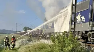 Feuerwehrmänner löschen eine brennende Lokomotive zwischen Weinheim-Lützelsachsen und Heddesheim/Hirschberg.