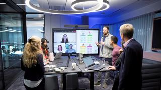 Beschäftigte von SAP bei einer Besprechung im Büro. Kolleginnen und Kollegen sind auch per Video zugeschaltet.
