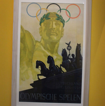 Plakat für die Olympischen Sommerspiele 1936 in Berlin: der Athlet mit martialischem Gesichtsausdruck und die Quadriga des Brandenburger Tores.