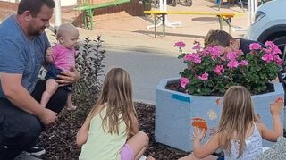 Kinder bemalten den Pflanzring im neu gestalteten Blumenbeet am Parkplatz Graben