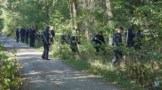 Nach dem Mord im Wald: Ein Suchtrupp der Polizei bei der Arbeit.