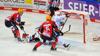 Mannheims Luke Esposito (Nr.19) gegen Bremerhavens Anders Groenlund (Nr.6) vor dem Tor von Bremerhavens Kristers Gudlevskis (Nr.30) beim Spiel der Adler Mannheim gegen Fischtown Pinguins Bremerhaven (rot).