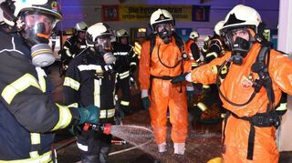 Nach der Übung wurden die Einsatzkräfte mit Wasser abgesprüht. Im Ernstfall werden die Schutzanzüge nach Ende des Einsatzes verbrannt.