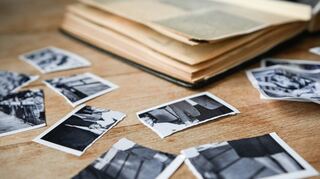 Zerrissene Kinderbilder liegen neben einem aufgeschlagenen Fotoalbum. Viele Missbrauchsopfer tragen die Folgen ein Leben lang.