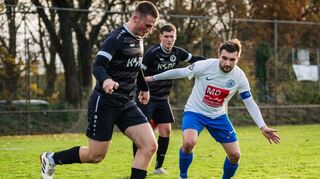Dustin Weißensteiner (links im schwarzen Trikot) von der SG Lindenfels/Winterkasten läuft mit dem Ball am Groß-Rohrheimer Kapitän Marcel Eckhardt vorbei.