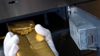 Gold sollte sicher aufbewahrt werden. Ein Mann legt einen Goldbarren in ein Schließfach in einem Tresorraum.